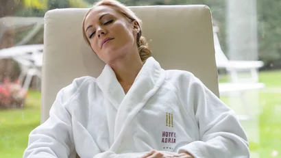Woman relaxing on lounge chair in bathrobe in hotel garden