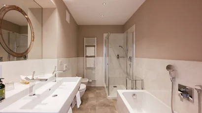 Modern bathroom with bathtub, shower, sink, and round mirror