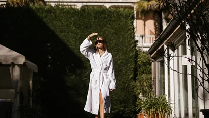 Woman in bathrobe walking in garden in front of Hotel Adria on a sunny day