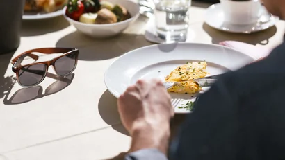 Person eating omelette at table with water and bread