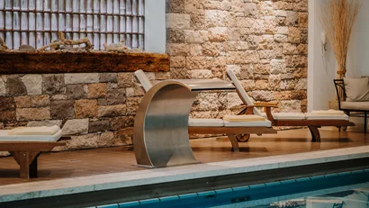 Indoor pool with lounge chairs and stone wall in spa area