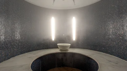 Circular steam bath cabin with mosaic tiles and central bowl