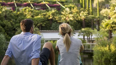 Couple sitting by pond looking at terraced garden and castle