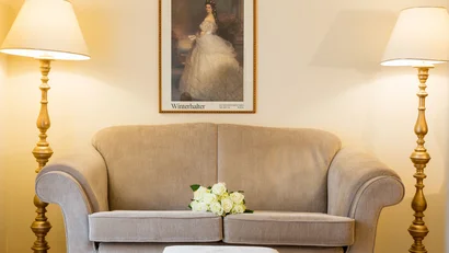 Beige sofa with white roses between two golden floor lamps