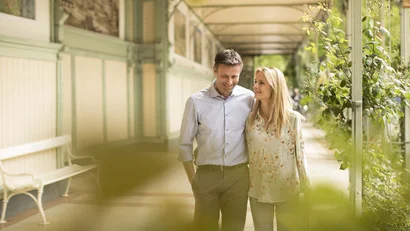 Couple walking in covered walkway with plants and benches