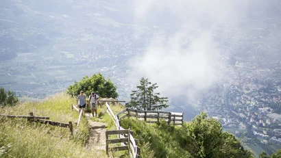 Two hikers on a path overlooking a misty valley and town