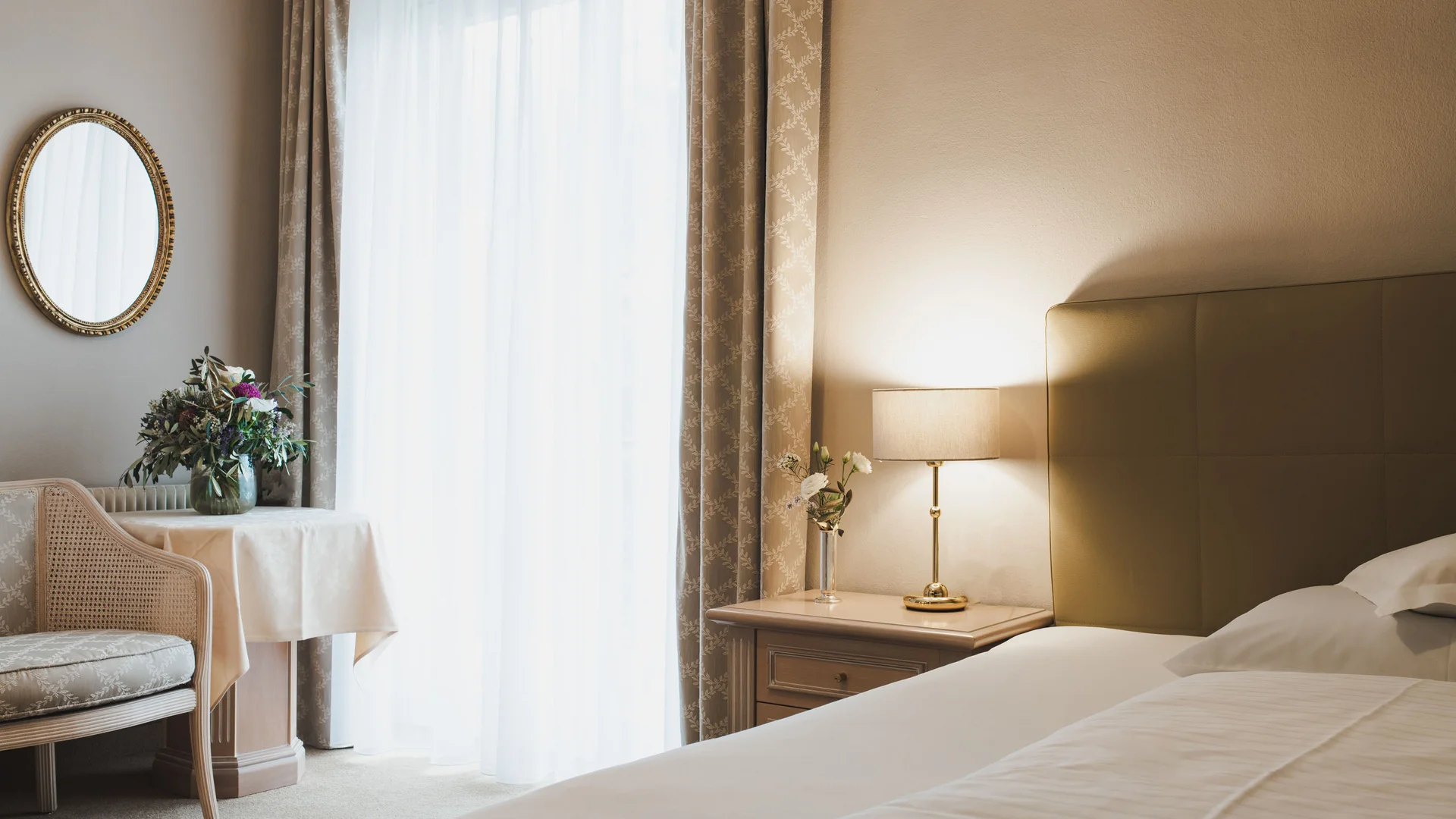 Cozy hotel room with bed, nightstand, lamp, and window with curtains