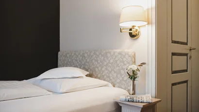 Cozy bedroom with patterned headboard and nightstand with lamp and flowers