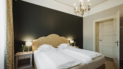 Bright bedroom with two single beds, dark gray wall, and floral patterned headboard